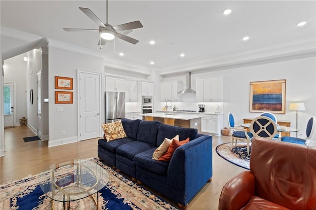 living room featuring crown molding, sink, light wood-type flooring, and ceiling fan