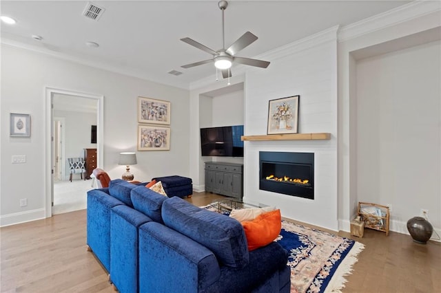 living room with ceiling fan, ornamental molding, light hardwood / wood-style flooring, and a fireplace