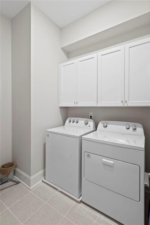 laundry area featuring washer and dryer, light tile patterned flooring, and cabinets