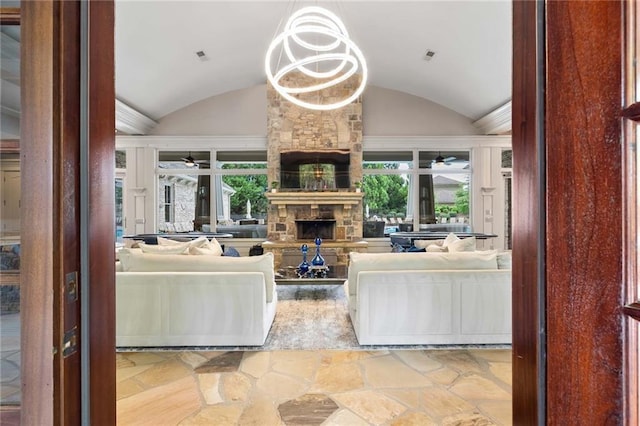 living room featuring a stone fireplace, lofted ceiling, and a chandelier