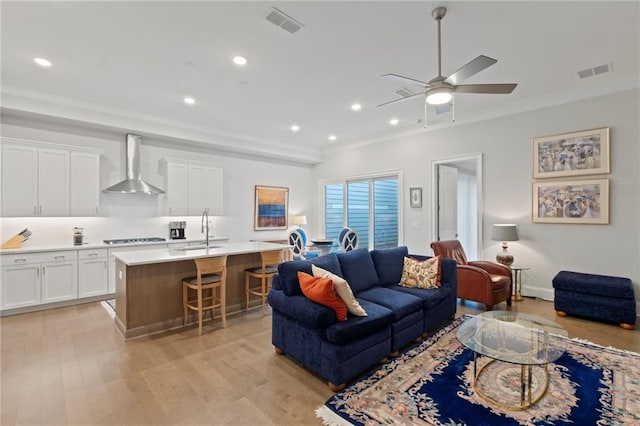 living room with light hardwood / wood-style floors, sink, and ceiling fan