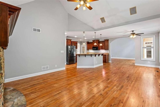 unfurnished living room with high vaulted ceiling, light hardwood / wood-style flooring, and ceiling fan