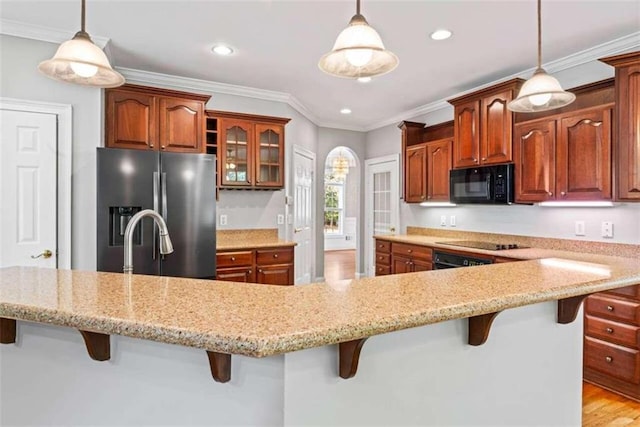 kitchen featuring black appliances, pendant lighting, a kitchen bar, and crown molding