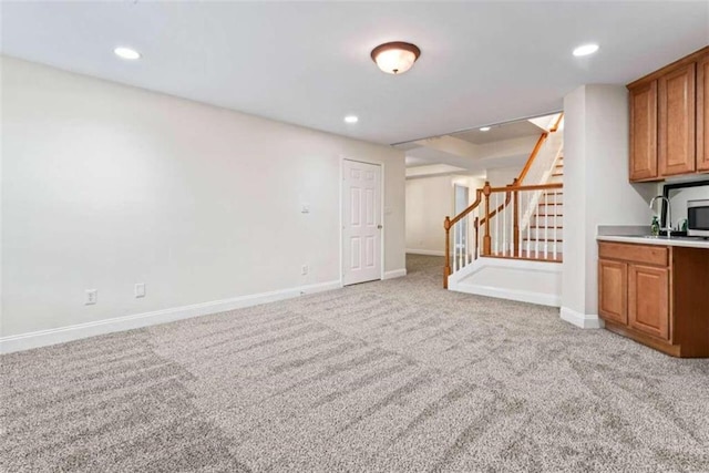 unfurnished living room with light carpet and sink