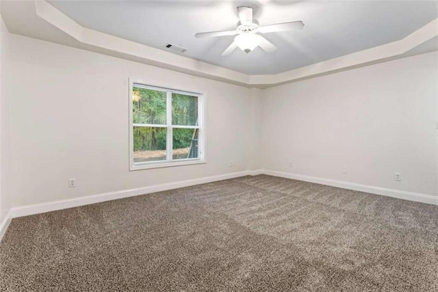 carpeted spare room featuring a tray ceiling and ceiling fan