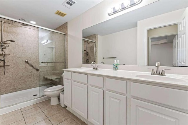 bathroom featuring tile patterned flooring, vanity, toilet, and a shower with door