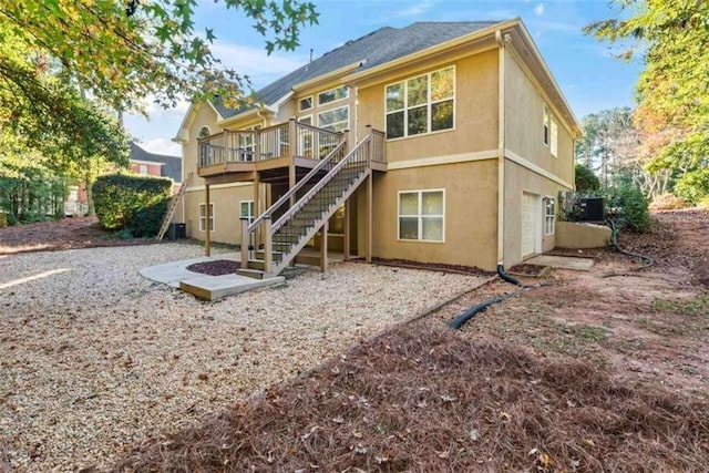 back of property featuring cooling unit, a garage, and a wooden deck