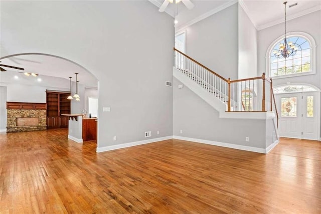 foyer featuring a towering ceiling, wood-type flooring, ceiling fan with notable chandelier, and ornamental molding