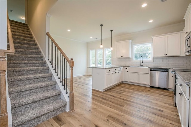 kitchen with light wood-style flooring, a sink, tasteful backsplash, stainless steel appliances, and a peninsula