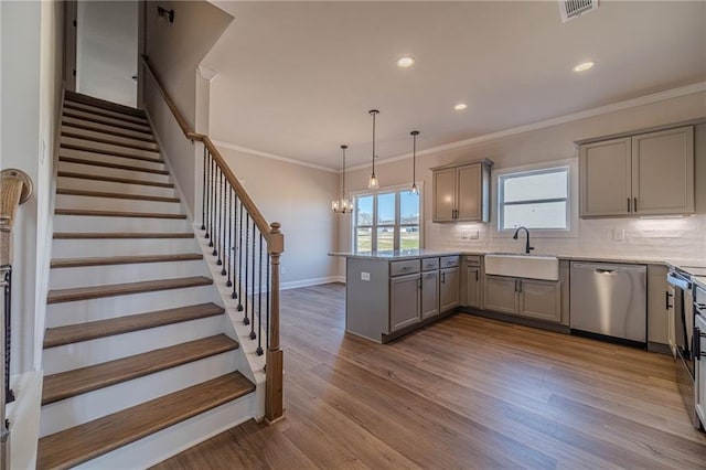 kitchen with backsplash, dishwasher, gray cabinets, a peninsula, and a sink