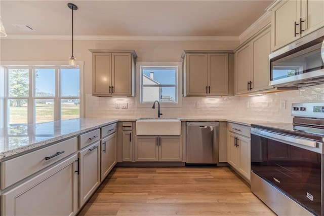 kitchen with light wood finished floors, tasteful backsplash, ornamental molding, stainless steel appliances, and a sink