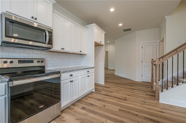 kitchen featuring tasteful backsplash, crown molding, light wood-style flooring, stainless steel appliances, and white cabinetry