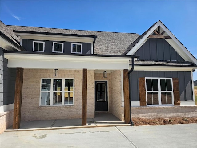 view of front facade with covered porch, brick siding, and board and batten siding