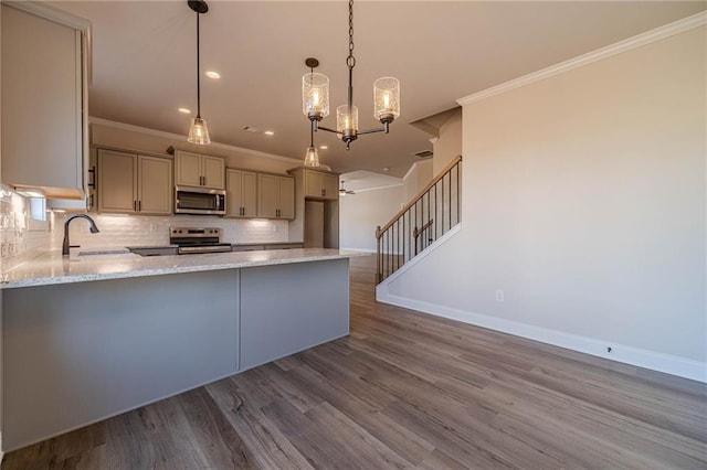 kitchen featuring a sink, backsplash, wood finished floors, stainless steel appliances, and light stone countertops