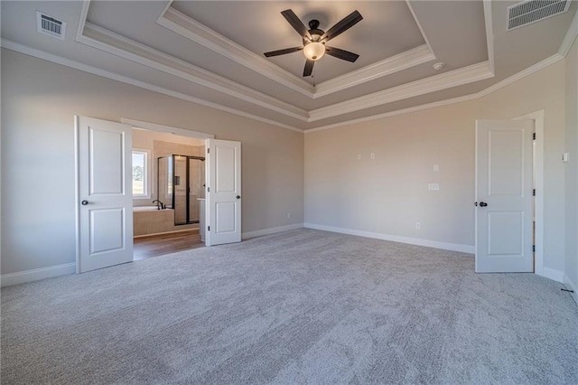 spare room featuring visible vents, a raised ceiling, and carpet