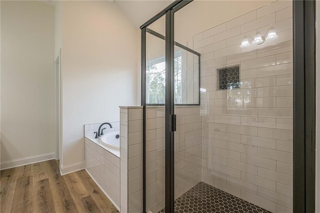 bathroom featuring a garden tub, wood finished floors, a stall shower, and baseboards