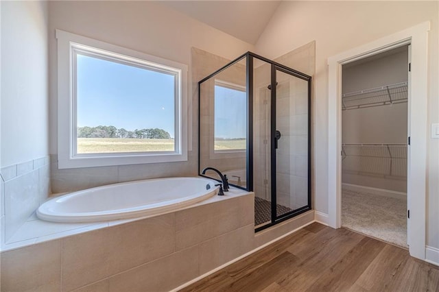 bathroom with a garden tub, a stall shower, wood finished floors, lofted ceiling, and a spacious closet