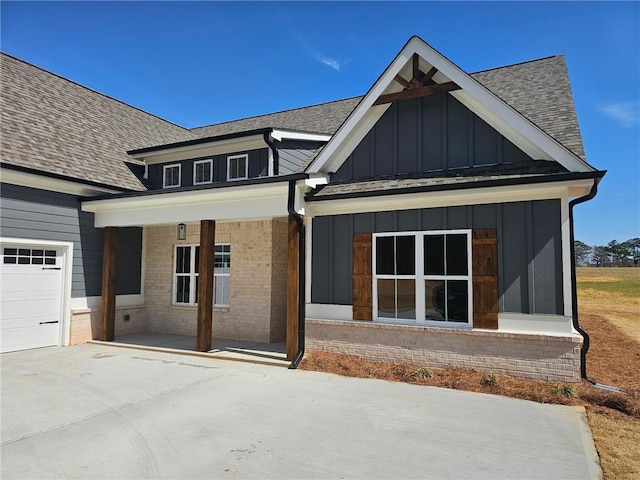 exterior space with covered porch, brick siding, board and batten siding, and roof with shingles