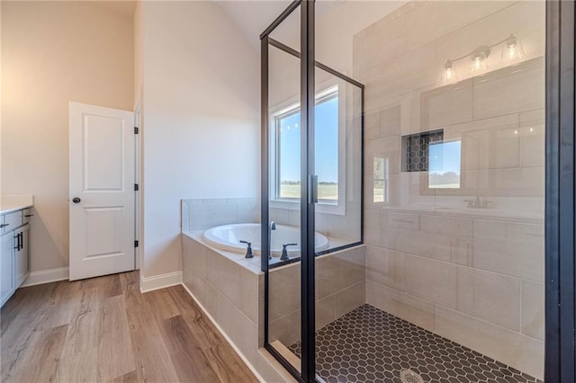 full bathroom featuring a shower stall, vaulted ceiling, wood finished floors, a bath, and vanity