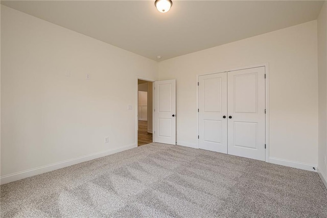 unfurnished bedroom featuring baseboards, carpet floors, and a closet