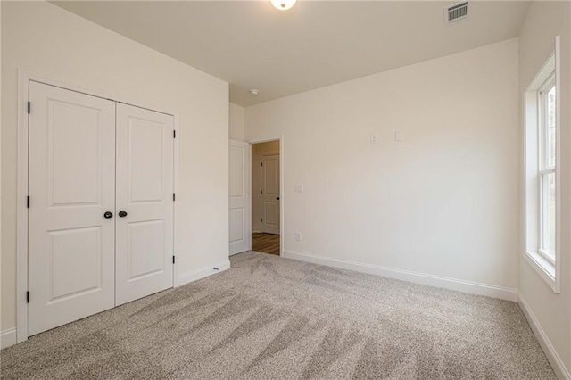 unfurnished bedroom featuring carpet flooring, baseboards, visible vents, and a closet