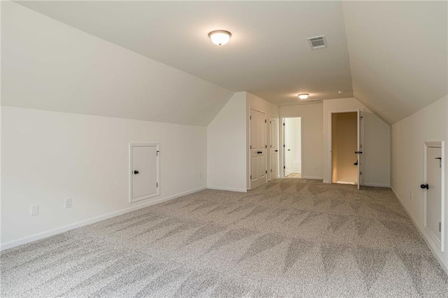 additional living space with baseboards, visible vents, carpet floors, and lofted ceiling