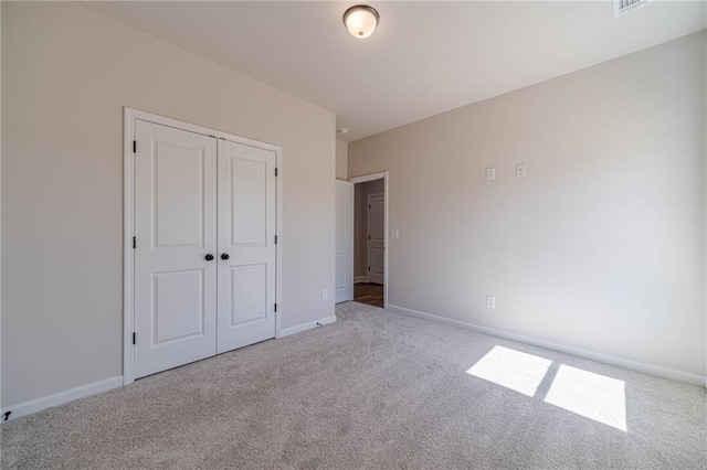 unfurnished bedroom featuring baseboards, carpet floors, and a closet