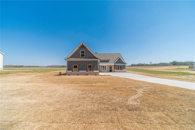 view of front of house with board and batten siding, concrete driveway, and a front lawn