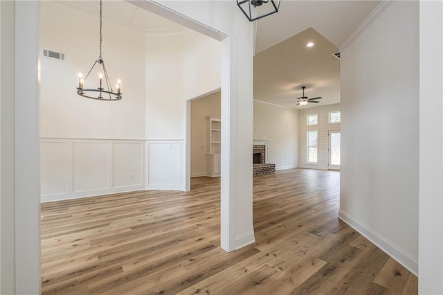 interior space with a decorative wall, visible vents, crown molding, and light wood-style floors