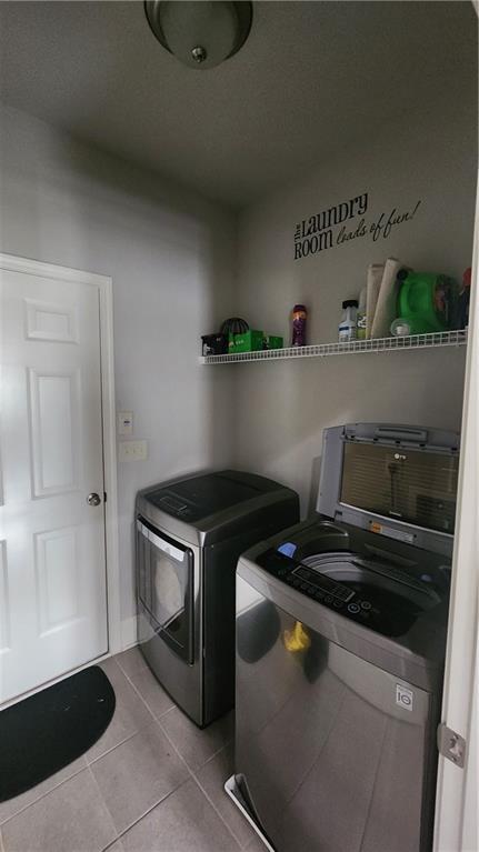laundry room with tile patterned floors, washer and clothes dryer, and laundry area
