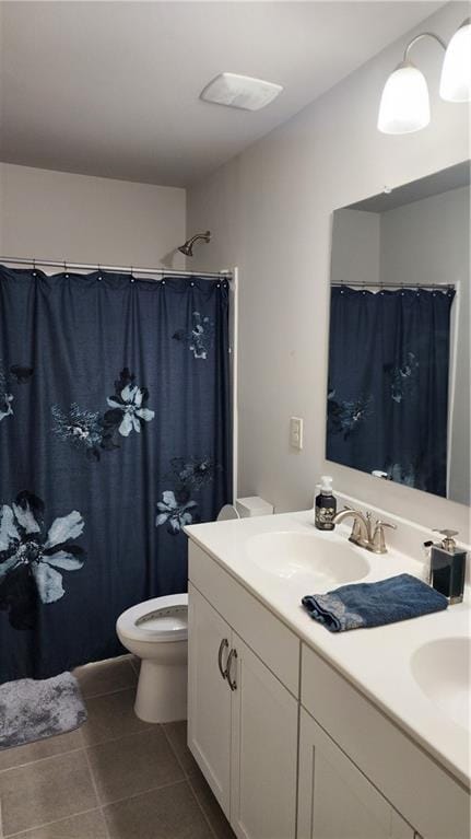 bathroom featuring toilet, double vanity, a sink, and tile patterned floors