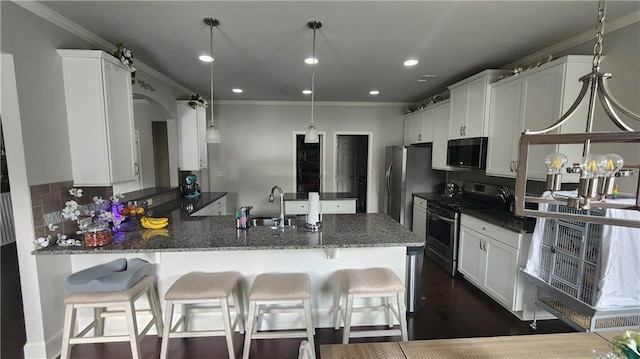 kitchen featuring a sink, stainless steel appliances, a peninsula, ornamental molding, and white cabinets