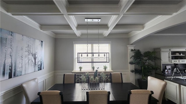 dining area featuring arched walkways, coffered ceiling, a decorative wall, beamed ceiling, and a wainscoted wall