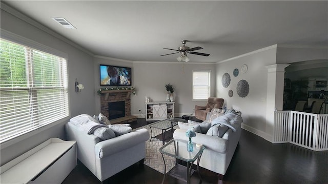 living room with baseboards, a stone fireplace, dark wood-style floors, visible vents, and a ceiling fan