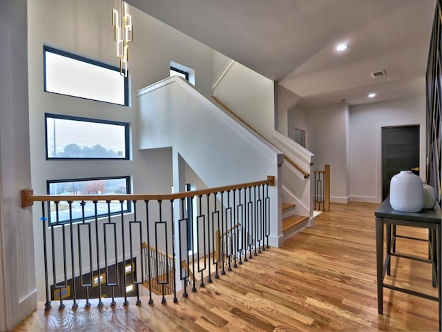 stairway with a towering ceiling and hardwood / wood-style flooring