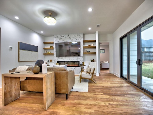 living room with a premium fireplace, a wealth of natural light, french doors, and light hardwood / wood-style floors