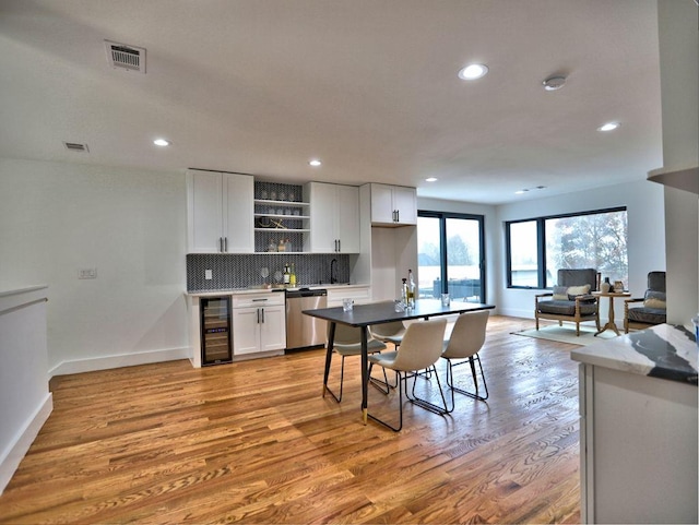 kitchen featuring dishwasher, beverage cooler, decorative backsplash, white cabinets, and light wood-type flooring