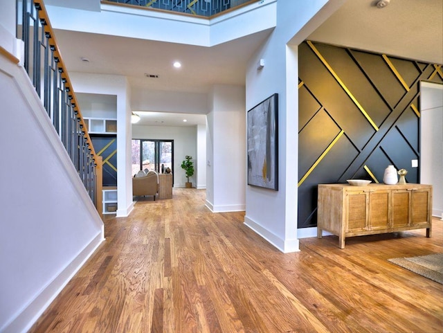 foyer entrance featuring wood-type flooring and a towering ceiling