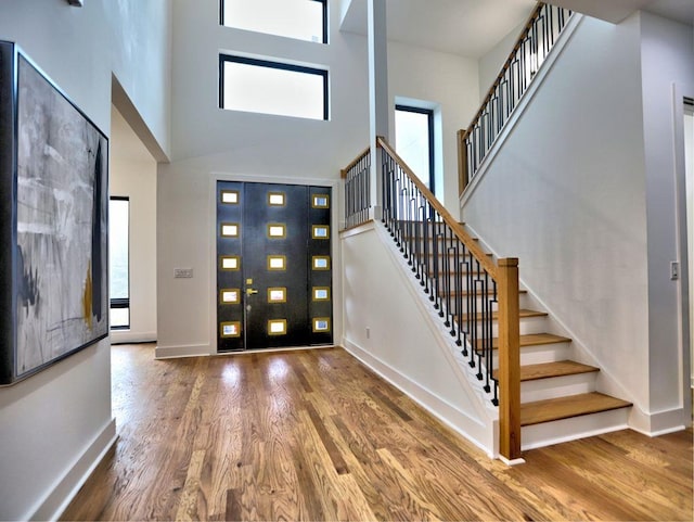 entryway with hardwood / wood-style floors and a towering ceiling