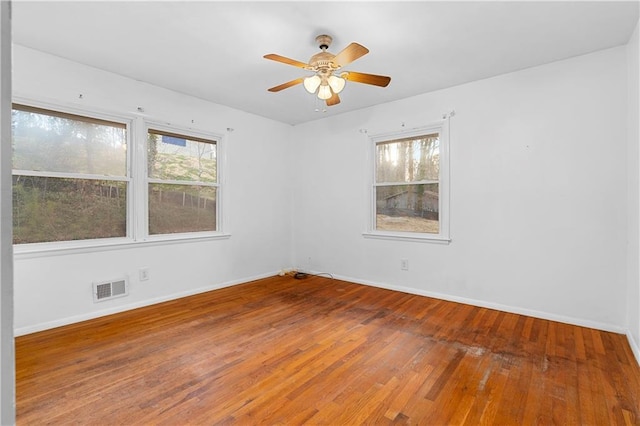 empty room featuring a ceiling fan, baseboards, visible vents, and hardwood / wood-style floors