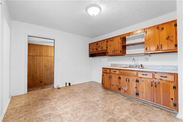 kitchen with brown cabinets, light countertops, a sink, and open shelves