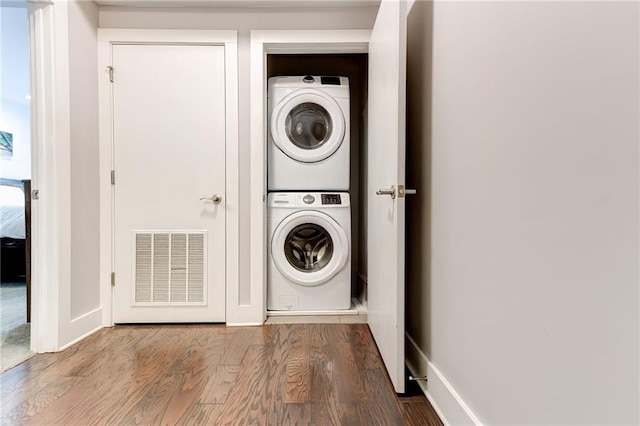 clothes washing area featuring stacked washer / dryer and wood-type flooring