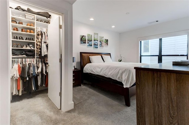 bedroom with a walk in closet, light colored carpet, and a closet