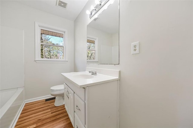 bathroom featuring vanity, toilet, wood finished floors, and visible vents