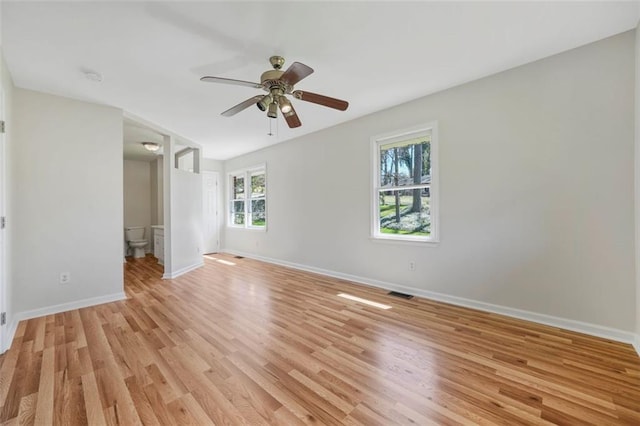 spare room featuring visible vents, baseboards, light wood-style flooring, and a ceiling fan