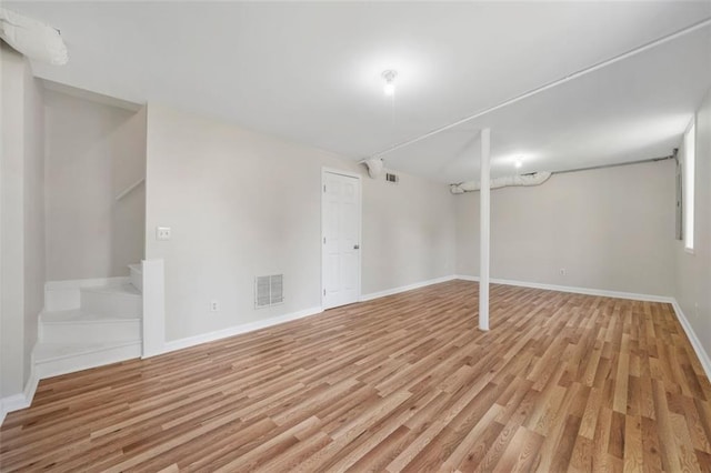 finished basement featuring light wood finished floors, visible vents, stairs, and baseboards