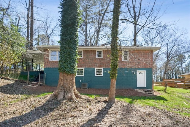 back of house featuring brick siding, cooling unit, and fence