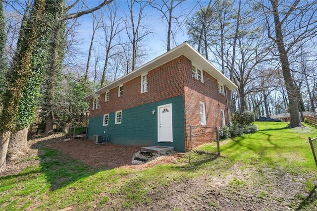 view of side of property featuring concrete block siding, a yard, and central AC