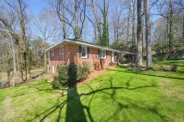 view of property exterior featuring a yard, fence, brick siding, and an attached garage