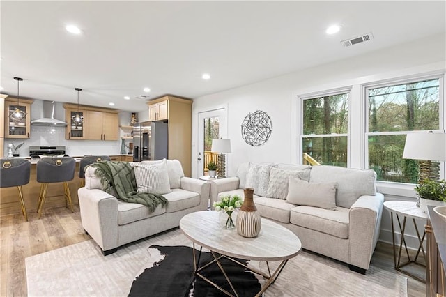 living area featuring recessed lighting, light wood-style floors, and visible vents